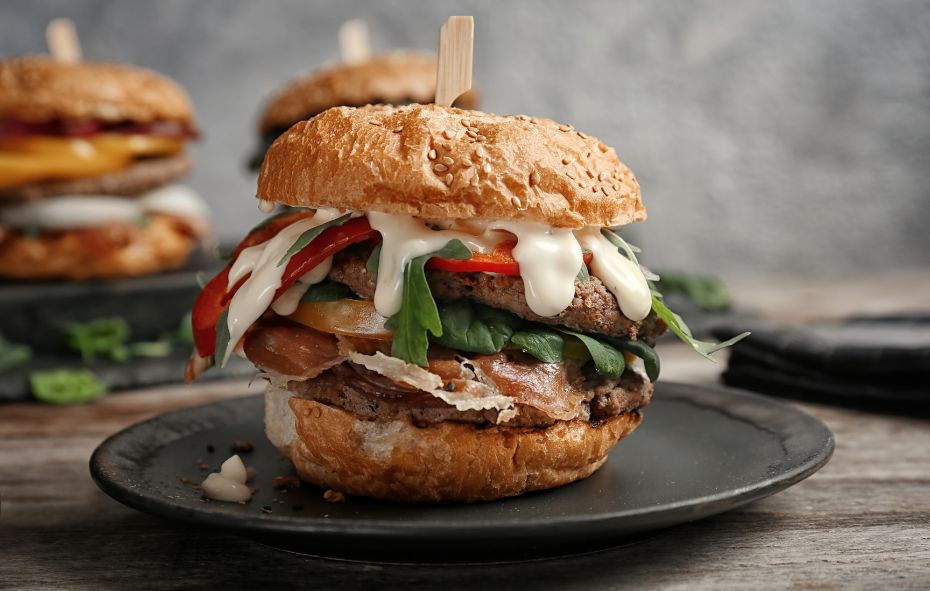 Broodje runderburger met rucola, tomaat, rode paprika en rauwe ham