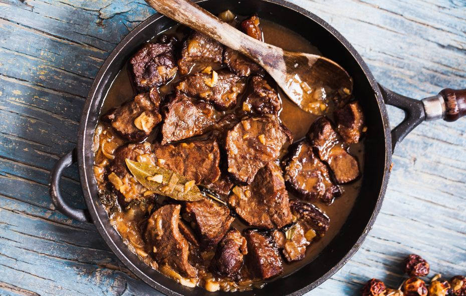 Een steelpan gevuld met stukken poulet, gestoofd tot een stoofpot