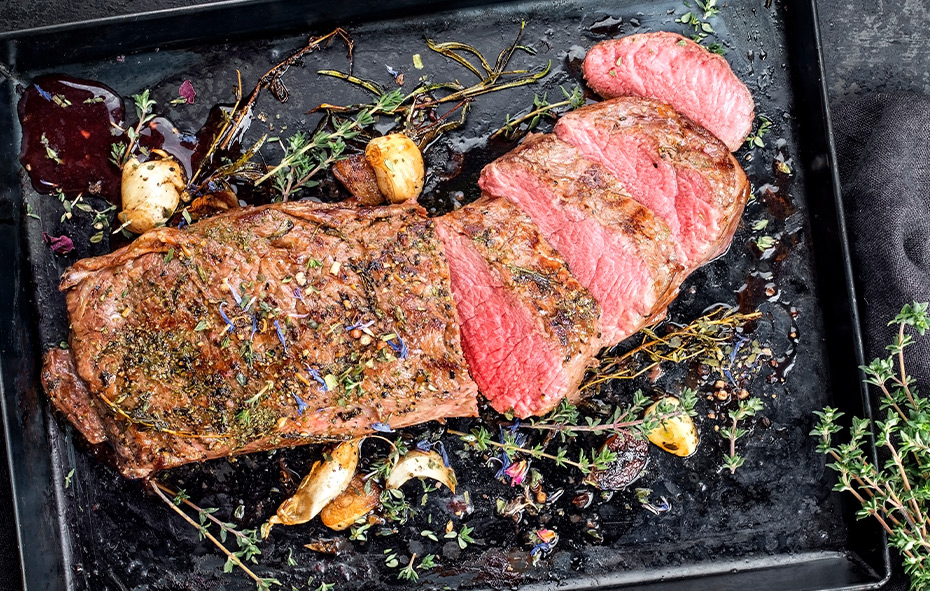 Afbeelding van een aangesneden gegrilde reerugfilet van de barbecue met diverse kleurrijke kruiden.