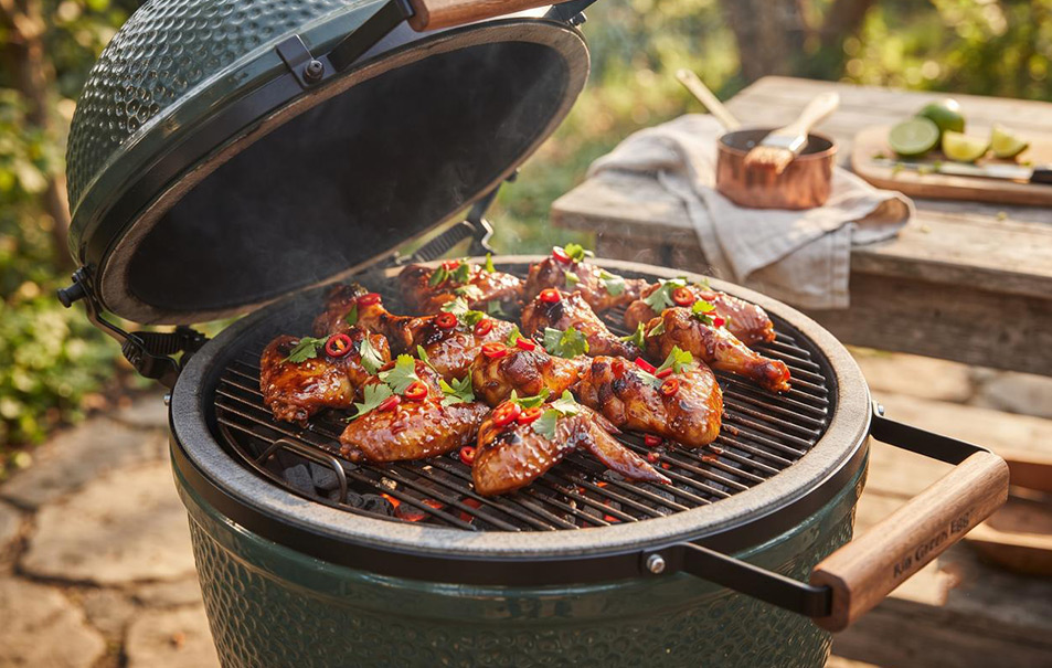 Krokante sticky chili-limoen kippenvleugeltjes van de barbecue, glanzend gelakt met een zoete chilisaus en gegarneerd met rode peper en limoen.