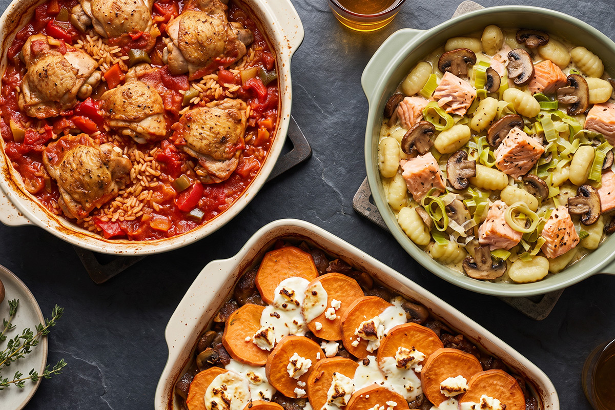 Drie ovenschotels van bovenaf: kip in tomaten-paprikasaus met rijst, gnocchi met wilde zalm, prei en champignons, en hertengehakt met zoete aardappel en geitenkaas